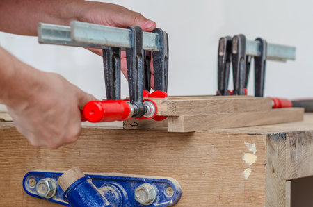Fastening carpentry clamps on a wooden frame in a carpentry workshop, gluing boardsの写真素材