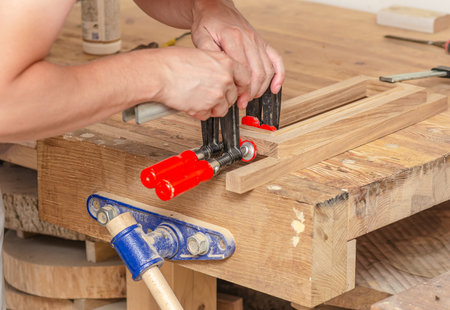 Fastening carpentry clamps on a wooden frame in a carpentry workshop, gluing boardsの写真素材