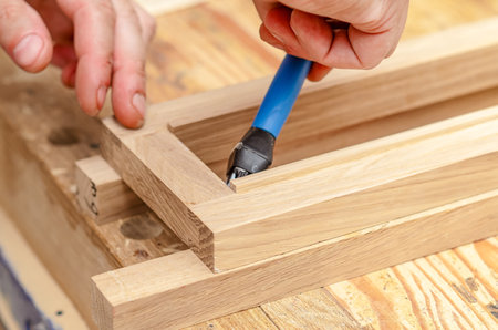 carpenter applies glue with a brush to wooden boards in the workshopの写真素材