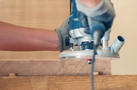 Smoothing the edges of a wooden board with a hand router, close-up on fine craftsmanshipの写真素材