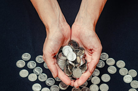 Close up of silver coins in female hands on black studio background. Aid to the poor, donatingの写真素材