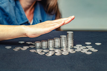 Female hand over coins in stacks. Symbol of profit growth, counting money. Blurred studio backgroundの写真素材