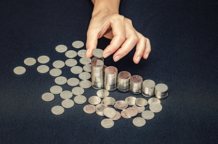 Female fingers puts coin on pile. Profit growth symbol, money counting, business investment conceptの写真素材