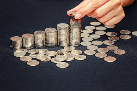 Female fingers puts coin on pile. Profit growth symbol, money counting, business investment conceptの写真素材