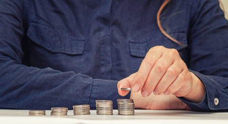 Coin in fingers of woman. Rising growth step, saving money, business investment concept. Blurred backgroundの写真素材