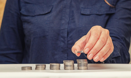 Woman's hand puts coin on pile. Rising growth step, money saving, business investment finance...