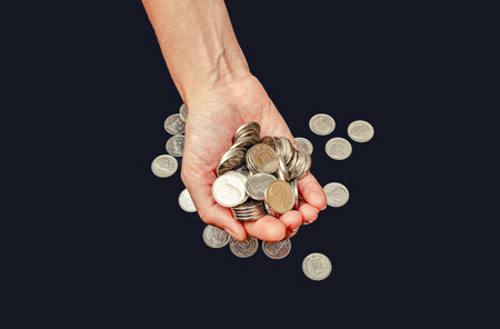 Close up silver coins in one female palm against black. Receiving financial assistance, donationsの写真素材