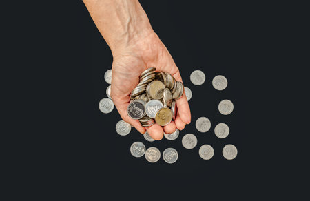 Close up silver coins in one female palm against black. Receiving financial assistance, donationsの写真素材