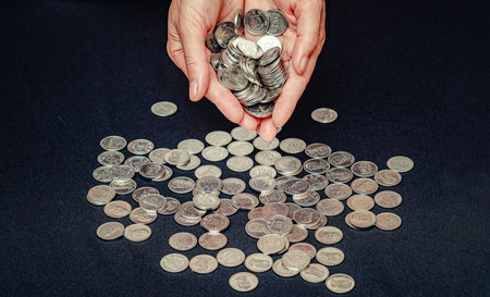 Close up of silver coins in female hands against black. Provision of material assistance, donationsの写真素材