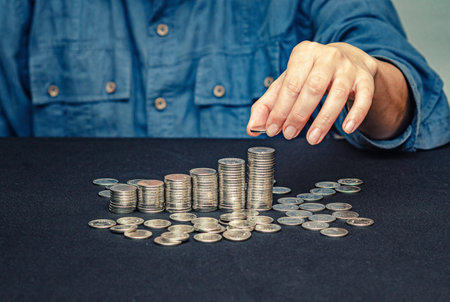 Coins in columns. Coin in fingers of woman. Step growth, saving money, investment business conceptの写真素材