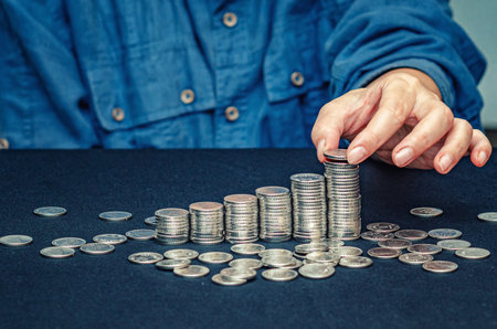 Concept of business, counting and saving money. Female hand counts and puts coins in columnsの写真素材