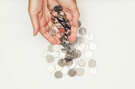 Coins fall from palms into pile. White background. Concept economic crisis, global recession, inflationの写真素材