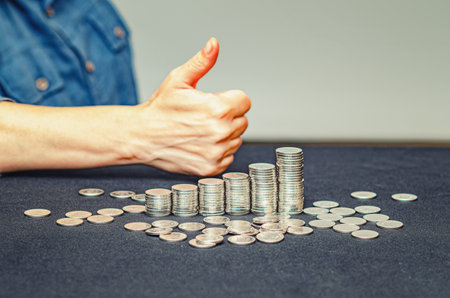 Thumb up hand with growing stacks of coins. Concept of business development and saving money. Blurrの写真素材