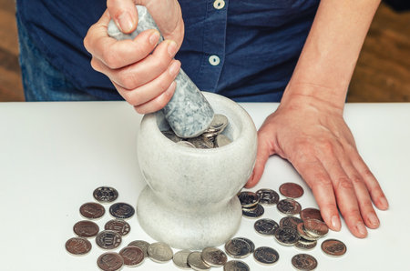 Hands pounding coins. Coins and porcelain mortar. Passive income and making money. Photo studioの写真素材