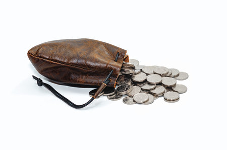 Pile of silver coins spilling out of leather pouch. Isolated on white background. Studio photoの写真素材