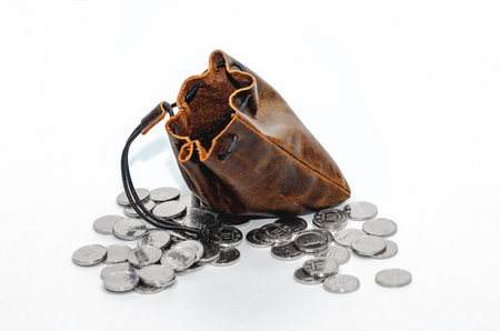 Pile of silver coins around an empty leather pouch. Isolated on white background. Studio photo.の写真素材