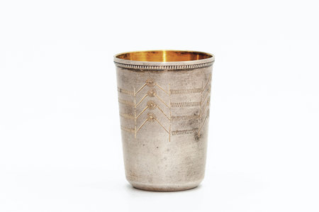 Small silver gilded antique vintage glass, isolated on white background. Metal glass with engraving patternの写真素材