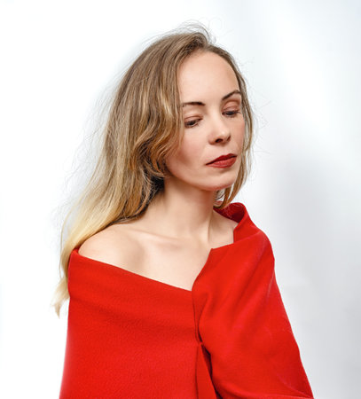 Charming blonde woman in red scarf, on white background. Bare shoulder, red lipstick. Looking downの写真素材