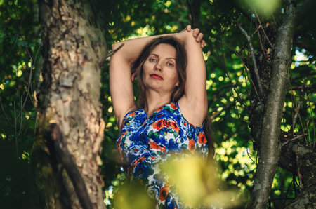 Adult woman on tree enjoying green nature. Forest around her. Concept of healthy natural lifestyle. Sun glareの写真素材