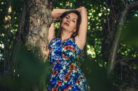 Colm lady on tree enjoying green nature. Forest around her. Concept of women and healthy natural lifestyleの写真素材