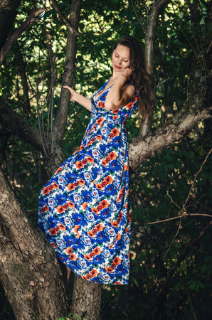 Adult lady on tree enjoying green nature. Forest around her. Concept of women and healthy natural lifestyleの写真素材