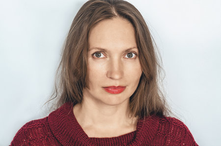 Portrait of an optimistic pleasant adult woman wearing red sweatshirt. Light smile. Gray backgroundの写真素材
