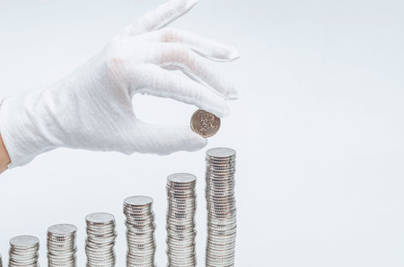 Business woman's hand in white glove showing coin. Concept of finance, investment, savings and bankingの写真素材