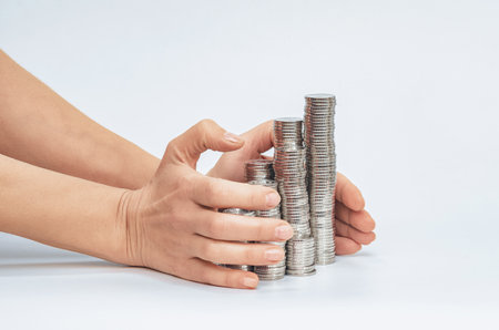 Concept of investment protection, insurance. Hands hugging stacks of coins on white. Fund, money saving, businessの写真素材