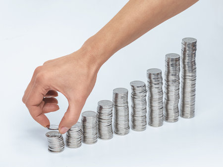 Female hand puts silver coin in column. Columns of coins. Concept of business, counting and saving moneyの写真素材