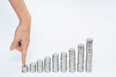 Female finger points coin in short column. Columns of silver coins in growth. Business opening, financial risksの写真素材