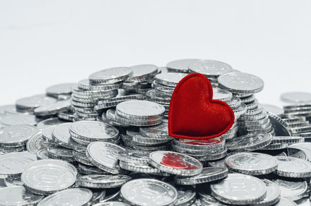 Pile of silver coins with red heart. Money for travel, jewelry, pleasure or charity. Selective focus. Copy spaceの写真素材