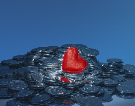 Valentine's Day greeting card. Red heart and silver coins against blue. Love and money. Place for textの写真素材