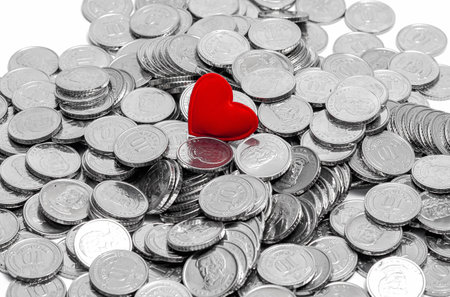 Background of silver coins with red heart. Money for travel, jewelry, pleasure or charity. Selective focusの写真素材
