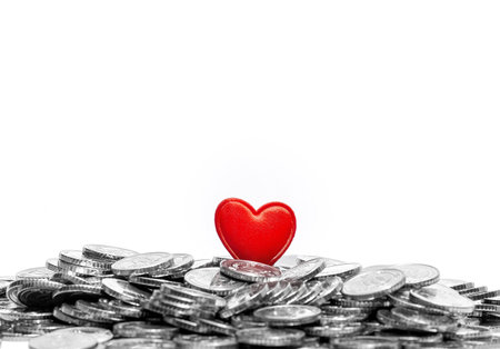 Small red heart on silver coins isolated on white. Love or money, love and money. Copy spaceの写真素材