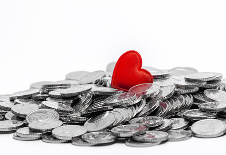 Small red heart on silver coins isolated on white. Love or money, love and money. Luck or thriftの写真素材