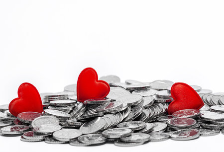 Pile of silver coins and three red hearts isolated on white. Idea for design. Valentine's Day cardの写真素材