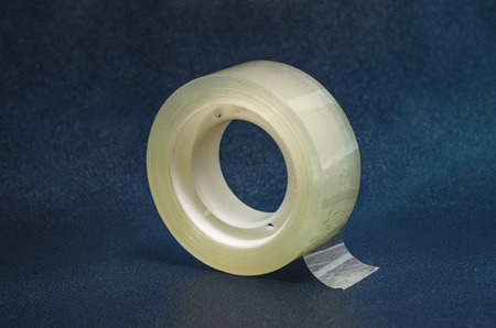 Roll of sticky transparent tape, roll of tape close up. Dark blue background, isolatedの写真素材