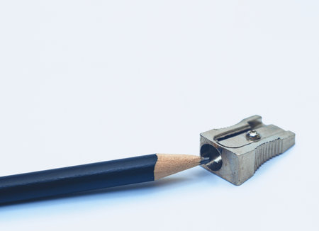 Sharpened black pencil lies next to metal sharpener. White background, isolated. Stationeryの写真素材