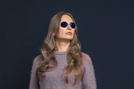 Adult woman with long hair wearing blue glasses looking away. Mysterious atmosphereの写真素材
