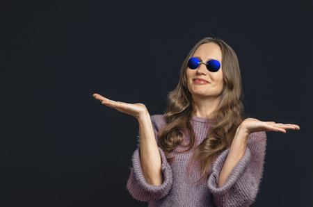 Surprised joyful woman on dark background. Woman in dark glasses with surprise pose, open arms. Copy spaceの写真素材