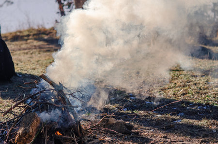 Cloudy smoke wafting from cooling campfire in grassy countryside at daybreak