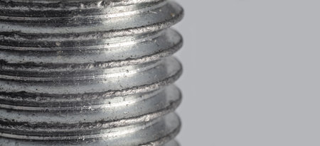 Close-up of metal screw threads with wear against gray background for industrial useの写真素材