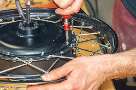 Hands of bicycle mechanic with screwdriver near electric motor. Repair of electric bicycles. Bicycle wheelの写真素材