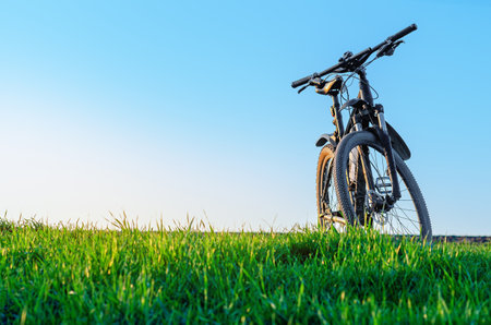 Sunlit bicycle on green field. Landscape with bicycle in spring. Outdoor recreation. Concept of cycling in nature. Copy spaceの写真素材