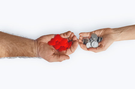 Mans hand with coins to womans hand with red hearts on white background, isolated. Love and money conceptの写真素材