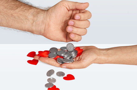 Coins from mans palm fall onto womans palm with red hearts. Problem of love for money. Donation conceptの写真素材