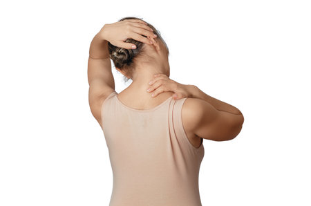 Woman in beige shirt  relaxes neck, stretching neck muscles. Tilts head to left for pain preventionの写真素材