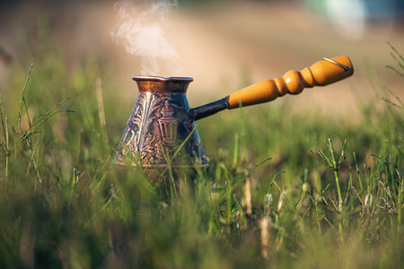 Aromatic coffee steams in copper engraved coffee pot on grass. Idea of outdoor recreation. Time to drink coffeeの写真素材