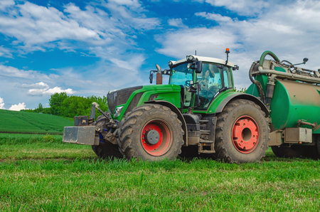 Agricultural machinery tractor standing in field. Large tractor. Side view. White cumulus clouds in backgroundの写真素材
