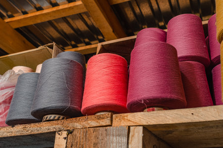 Multicolored knitting threads on wooden shelf. Colorful spools of thread in sock factory. Socks...